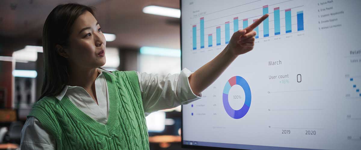 USA Student pointing to graph on monitor.